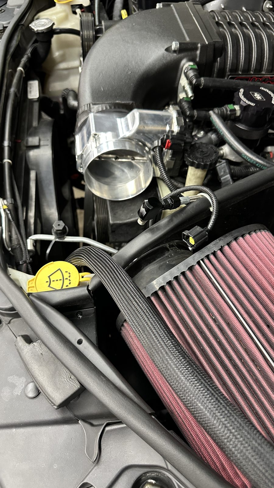 Red cone filter and throttle body detail in an engine bay